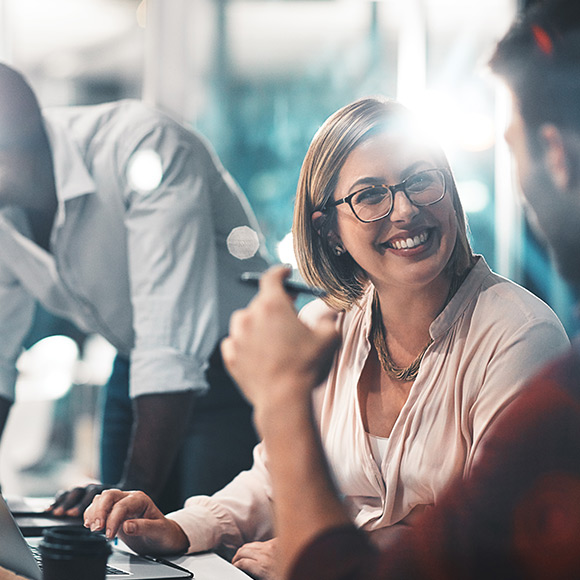 Woman smiling while using laptop and talking to man