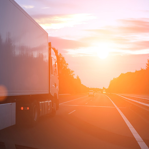 Large lorry driving down motorway at sunset