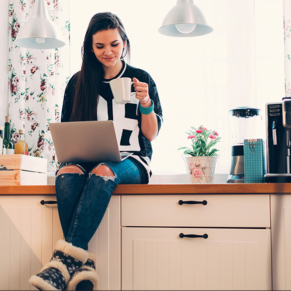 Young woman on laptop in kitchen